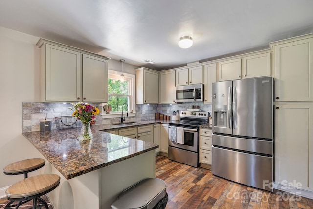 3980 English Oak Dr, Lincolnton, NC 28092 - kitchen featuring stainless steel appliances, a peninsula, tasteful backsplash, dark wood finished floors, and a kitchen bar