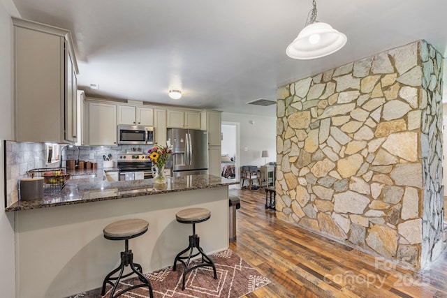 3980 English Oak Dr, Lincolnton, NC 28092 - kitchen featuring appliances with stainless steel finishes, dark stone countertops, dark wood-style flooring, backsplash, and a peninsula