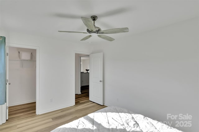 112 Aspire Cir, Wingate, NC 28174 - unfurnished bedroom with wood finished floors, a walk in closet, a closet, and a ceiling fan