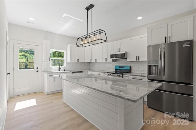 5526 Brookwood Ln, Hickory, NC 28602 - kitchen featuring appliances with stainless steel finishes, a kitchen island, light stone countertops, backsplash, and recessed lighting