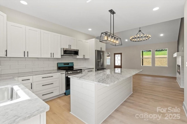 5526 Brookwood Ln, Hickory, NC 28602 - kitchen with appliances with stainless steel finishes, a center island, light wood-style flooring, decorative backsplash, and white cabinets