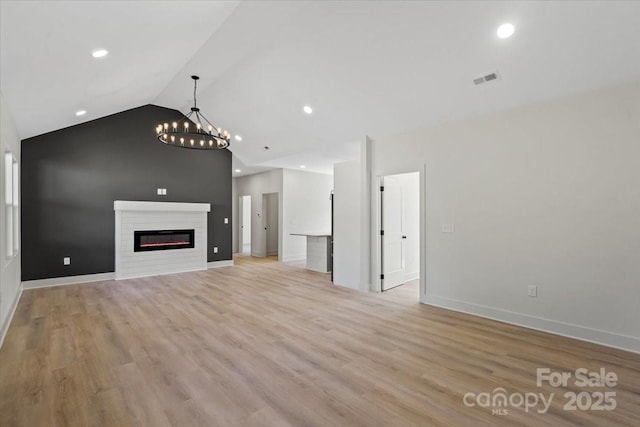 5526 Brookwood Ln, Hickory, NC 28602 - unfurnished living room featuring vaulted ceiling, a chandelier, light wood-style floors, a glass covered fireplace, and recessed lighting