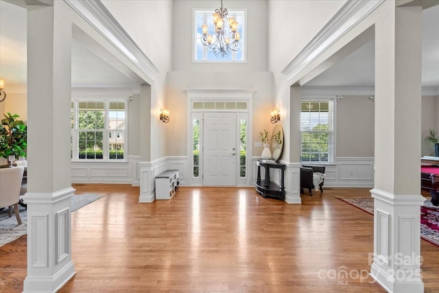 110 Isle Run Dr, Mooresville, NC 28117 - foyer featuring decorative columns, a decorative wall, a chandelier, wood finished floors, and a wainscoted wall