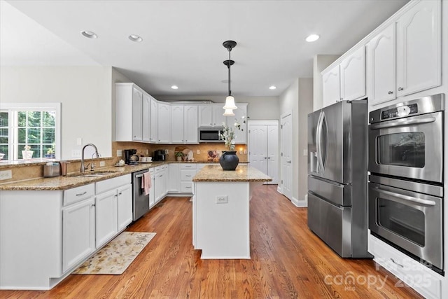 110 Isle Run Dr, Mooresville, NC 28117 - kitchen with appliances with stainless steel finishes, a center island, light stone countertops, light wood-style floors, and recessed lighting