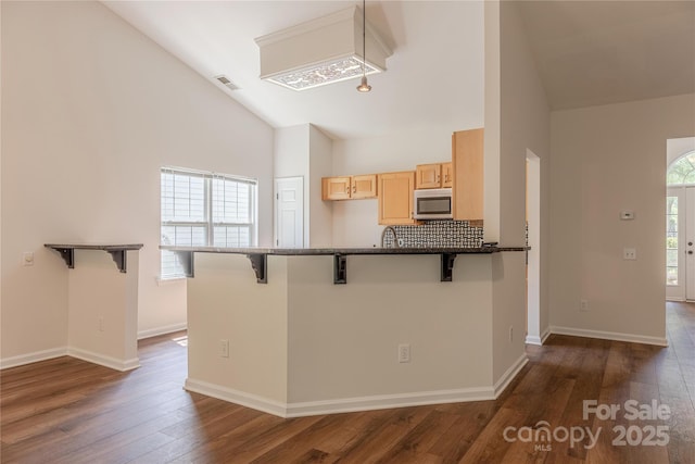 901 Clearbrook Rd, Matthews, NC 28105 - kitchen featuring light brown cabinetry, a breakfast bar area, dark wood-style floors, high vaulted ceiling, and a peninsula