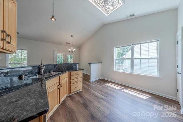 901 Clearbrook Rd, Matthews, NC 28105 - kitchen featuring light brown cabinetry, dark wood-type flooring, a chandelier, vaulted ceiling, and dark stone countertops