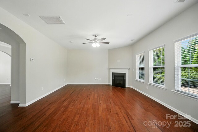 8115 Kelburn Ln, Charlotte, NC 28273 - unfurnished living room featuring wood finished floors, arched walkways, a fireplace with flush hearth, and a ceiling fan