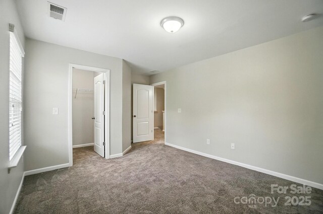 8115 Kelburn Ln, Charlotte, NC 28273 - unfurnished bedroom featuring carpet, multiple windows, a walk in closet, and a closet