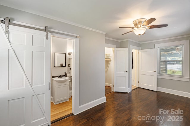 115 E Catawba St, Morganton, NC 28655 - unfurnished bedroom with dark wood-style flooring, a barn door, ornamental molding, ceiling fan, and ensuite bath