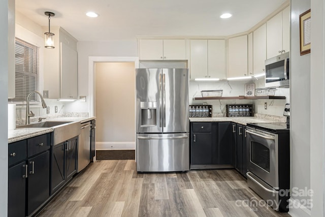 115 E Catawba St, Morganton, NC 28655 - kitchen with appliances with stainless steel finishes, light wood-style flooring, white cabinetry, dark cabinetry, and hanging light fixtures