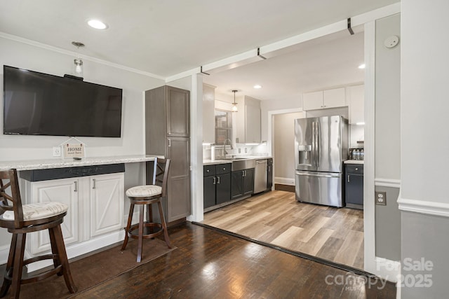 115 E Catawba St, Morganton, NC 28655 - kitchen featuring stainless steel appliances, light wood-style floors, a kitchen breakfast bar, white cabinets, and crown molding