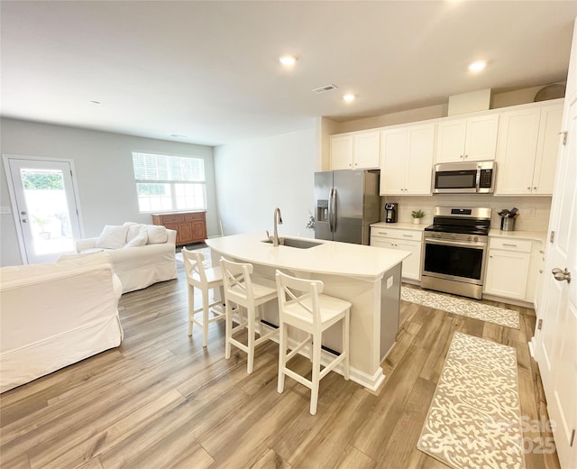 8060 Scarlet Maple Ln, Tega Cay, SC 29708 - kitchen featuring stainless steel appliances, open floor plan, decorative backsplash, light wood-style flooring, and a kitchen bar