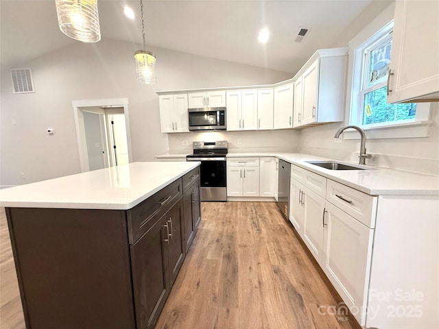 2330 Neill Rd, Lancaster, SC 29720 - kitchen featuring appliances with stainless steel finishes, vaulted ceiling, light wood finished floors, white cabinetry, and light countertops