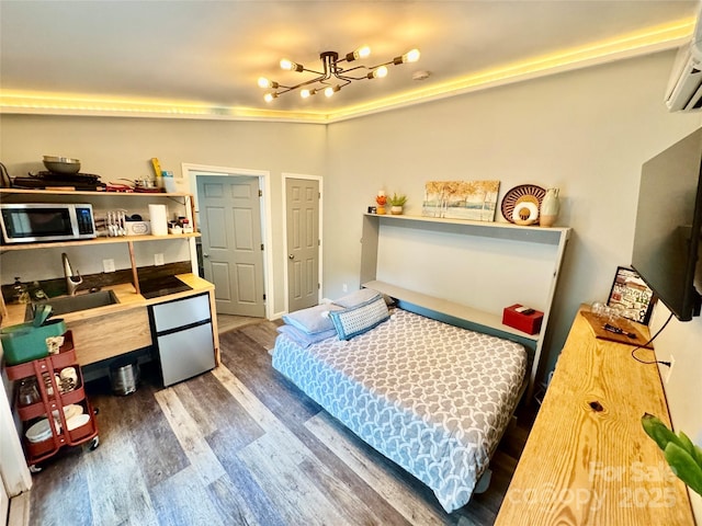 401 Church St, Warrenton, NC 27589 - bedroom featuring a chandelier, wood finished floors, fridge, and an AC wall unit