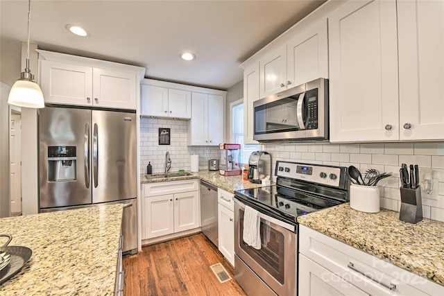 3020 Stancill Pl, Charlotte, NC 28205 - kitchen with stainless steel appliances, a sink, wood finished floors, white cabinets, and recessed lighting