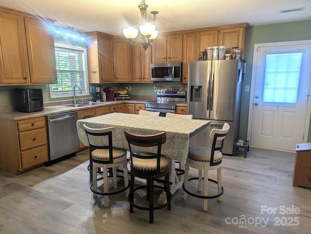 5077 Edney Ct, Granite Falls, NC 28630 - kitchen with appliances with stainless steel finishes, light countertops, light wood finished floors, a kitchen island, and pendant lighting