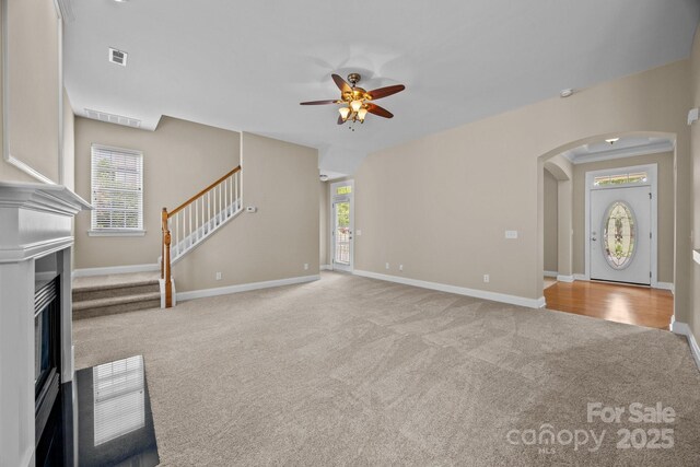 10349 Alvarado Way, Charlotte, NC 28277 - unfurnished living room featuring carpet flooring, arched walkways, a glass covered fireplace, a ceiling fan, and plenty of natural light