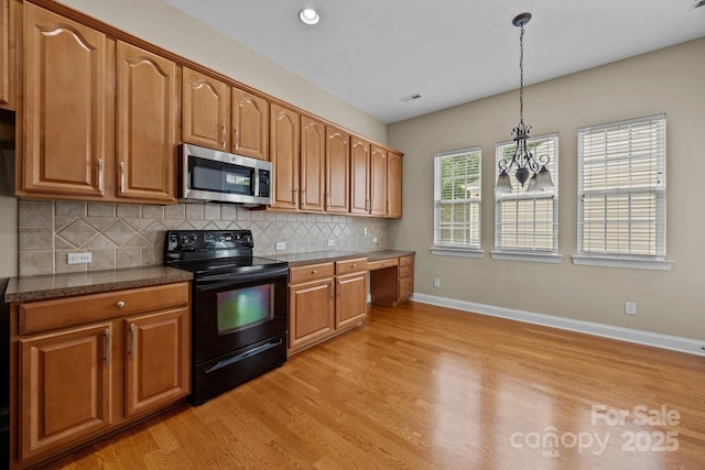 10349 Alvarado Way, Charlotte, NC 28277 - kitchen with black range with electric stovetop, stainless steel microwave, light wood-style floors, decorative backsplash, and brown cabinetry