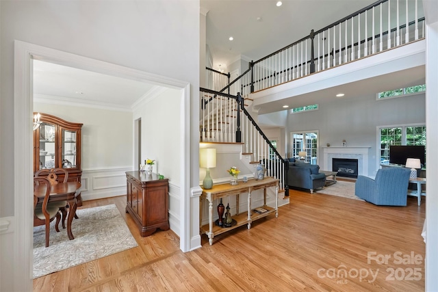 12644 Lahinch Ct, Charlotte, NC 28277 - staircase with wood finished floors, ornamental molding, a towering ceiling, a decorative wall, and a glass covered fireplace