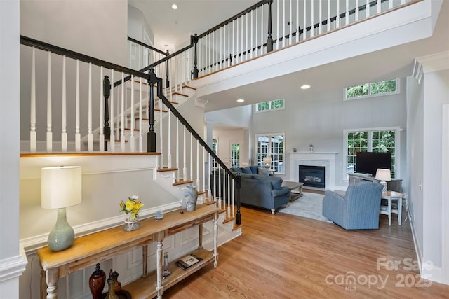 12644 Lahinch Ct, Charlotte, NC 28277 - stairs featuring a towering ceiling, a glass covered fireplace, wood finished floors, and recessed lighting