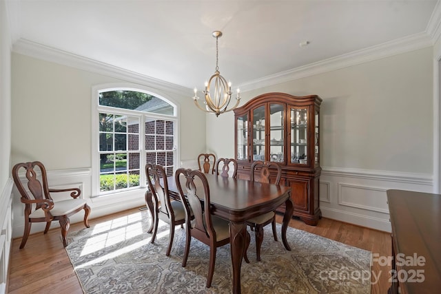 12644 Lahinch Ct, Charlotte, NC 28277 - dining area featuring a chandelier, crown molding, wood finished floors, wainscoting, and a decorative wall