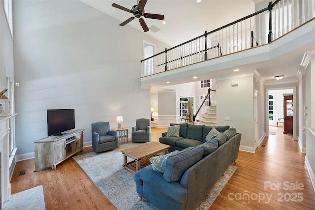 12644 Lahinch Ct, Charlotte, NC 28277 - living room featuring stairs, a ceiling fan, crown molding, a high ceiling, and light wood-style flooring