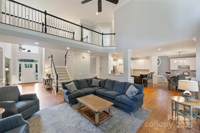 12644 Lahinch Ct, Charlotte, NC 28277 - living area featuring a towering ceiling, light wood finished floors, a ceiling fan, ornamental molding, and stairs