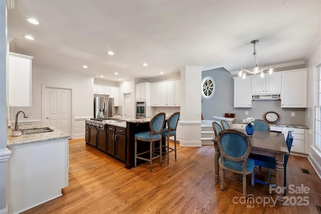 12644 Lahinch Ct, Charlotte, NC 28277 - kitchen with stainless steel appliances, under cabinet range hood, ornamental molding, light stone countertops, and white cabinetry