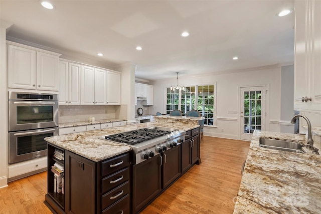 12644 Lahinch Ct, Charlotte, NC 28277 - kitchen with appliances with stainless steel finishes, white cabinetry, a kitchen island, ornamental molding, and recessed lighting