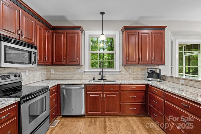 17433 Glassfield Dr, Huntersville, NC 28078 - kitchen featuring stainless steel appliances, light wood-style flooring, reddish brown cabinets, and decorative backsplash