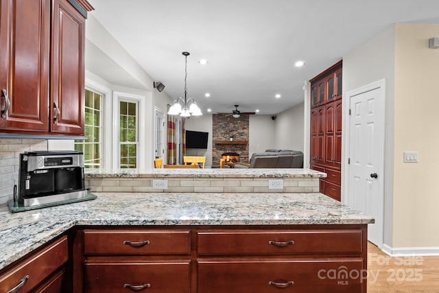 17433 Glassfield Dr, Huntersville, NC 28078 - kitchen featuring reddish brown cabinets, a peninsula, backsplash, light stone counters, and recessed lighting