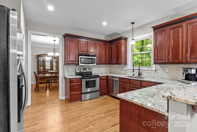 17433 Glassfield Dr, Huntersville, NC 28078 - kitchen featuring appliances with stainless steel finishes, light wood finished floors, decorative light fixtures, dark brown cabinets, and ornamental molding