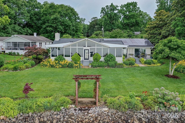 7945 Placid Ct, Denver, NC 28037 - rear view of house with roof mounted solar panels, a sunroom, a yard, and a chimney