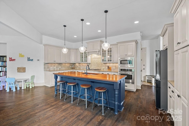 109 Walking Horse Trl, Davidson, NC 28036 - kitchen with appliances with stainless steel finishes, butcher block countertops, dark wood-style flooring, backsplash, and recessed lighting