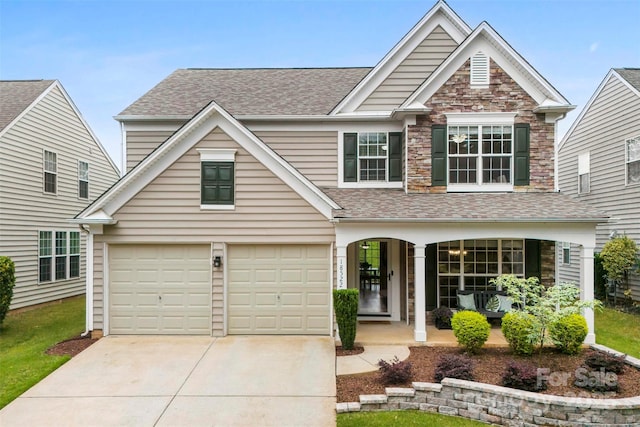 18522 Victoria Bay Dr, Cornelius, NC 28031 - traditional home with covered porch, concrete driveway, roof with shingles, stone siding, and a garage