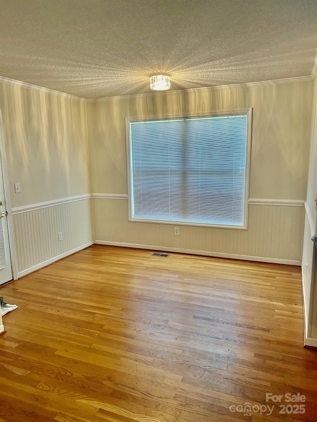 1700 Pickwick Ave, Kannapolis, NC 28083 - spare room featuring a textured ceiling, wood finished floors, a wainscoted wall, and crown molding