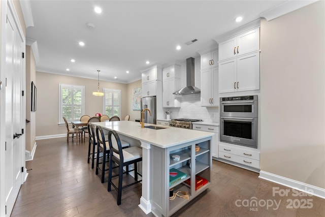 318 N Dotger Ave, Charlotte, NC 28204 - kitchen with wall chimney exhaust hood, appliances with stainless steel finishes, a kitchen breakfast bar, an island with sink, and backsplash