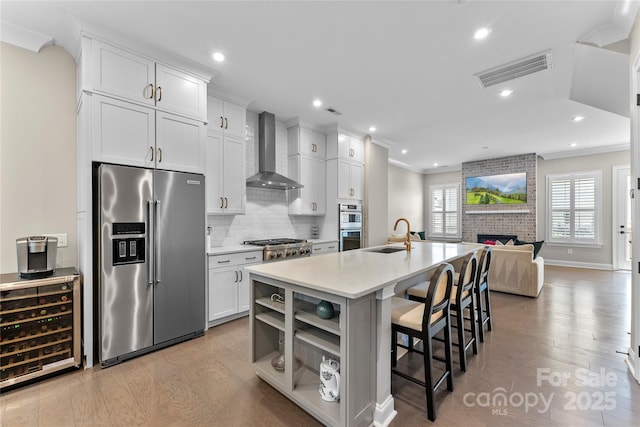 318 N Dotger Ave, Charlotte, NC 28204 - kitchen with appliances with stainless steel finishes, wall chimney range hood, wood finished floors, beverage cooler, and a breakfast bar