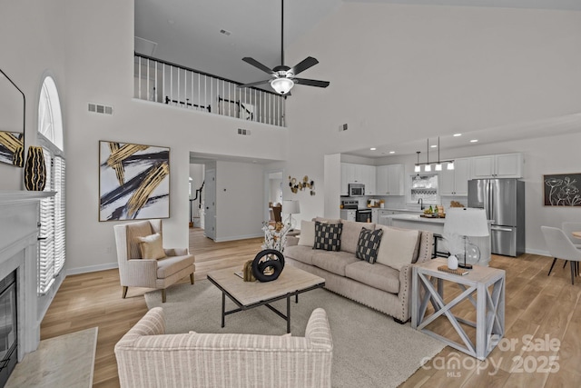 7213 Baniff Cir, Charlotte, NC 28277 - living area featuring light wood-style flooring, a ceiling fan, a high ceiling, healthy amount of natural light, and a high end fireplace