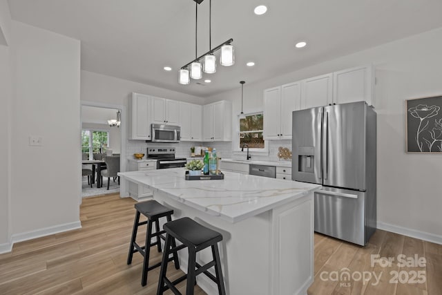 7213 Baniff Cir, Charlotte, NC 28277 - kitchen featuring stainless steel appliances, white cabinetry, tasteful backsplash, light wood-style flooring, and pendant lighting