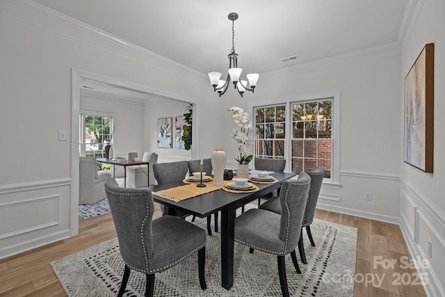 7213 Baniff Cir, Charlotte, NC 28277 - dining area featuring a chandelier, light wood-style floors, crown molding, and wainscoting