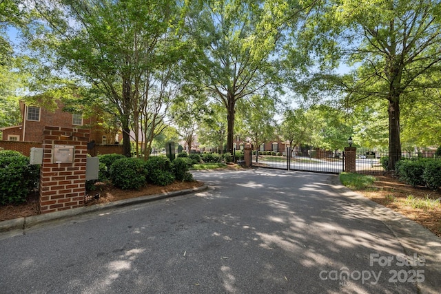 7213 Baniff Cir, Charlotte, NC 28277 - view of asphalt road with a gate and curbs