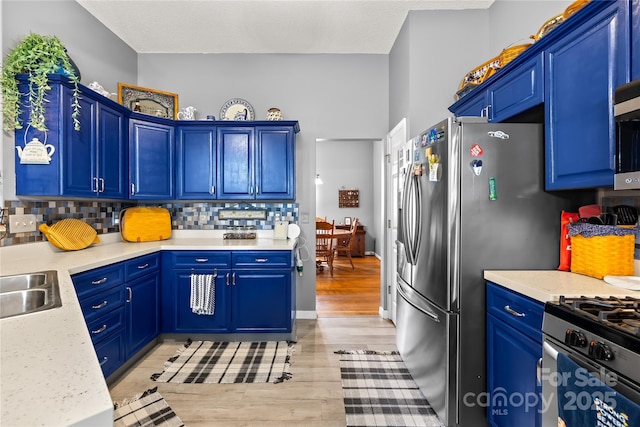 256 Rose St, Mooresville, NC 28117 - kitchen featuring light wood-type flooring, light countertops, tasteful backsplash, appliances with stainless steel finishes, and blue cabinetry