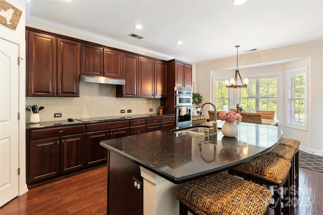 2504 River Oaks Dr, Waxhaw, NC 28173 - kitchen featuring dark wood-type flooring, double oven, ornamental molding, a kitchen bar, and a chandelier