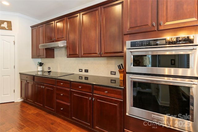 2504 River Oaks Dr, Waxhaw, NC 28173 - kitchen featuring stainless steel double oven, black electric cooktop, under cabinet range hood, dark wood finished floors, and crown molding