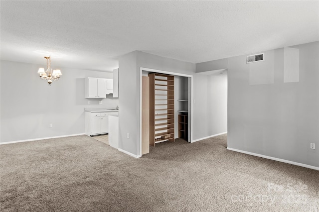 2205 Sunderland Rd Unit 129D, Winston Salem, NC 27103 - unfurnished living room with light colored carpet, a chandelier, baseboards, a textured ceiling, and a sink