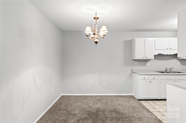 2205 Sunderland Rd Unit 129D, Winston Salem, NC 27103 - kitchen with a sink, white cabinetry, a chandelier, light countertops, and a textured ceiling