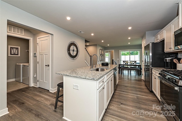124 Kristin View Ln Unit Townhome A, Troutman, NC 28166 - kitchen featuring washer and clothes dryer, stainless steel appliances, a breakfast bar, a center island with sink, and white cabinets