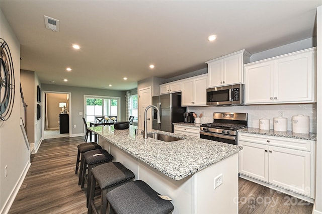 124 Kristin View Ln Unit Townhome A, Troutman, NC 28166 - kitchen with stainless steel appliances, white cabinetry, an island with sink, dark wood-style floors, and a kitchen breakfast bar