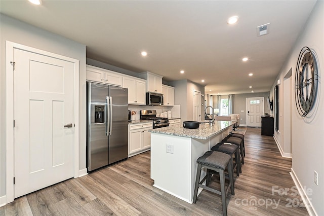124 Kristin View Ln Unit Townhome A, Troutman, NC 28166 - kitchen with stainless steel appliances, white cabinetry, a kitchen island with sink, recessed lighting, and a kitchen bar